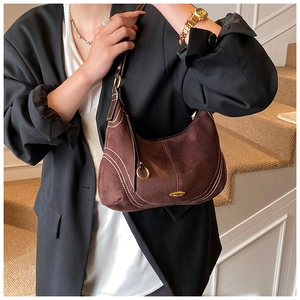 Close-up of deep brown suede hobo bag with contrast stitching and gold logo plaque