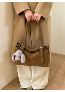Detail of a brown retro tote bag featuring a silver metal ring and cute plush rabbit charm