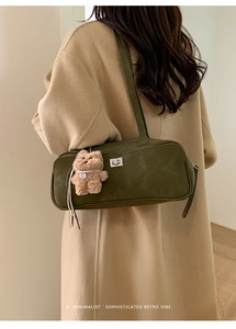 Detalle del bolso de hombro en ante verde oliva con cierre plateado y oso de peluche
