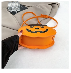 Close-up of a stylish orange pumpkin-shaped crossbody bag with a black flap and strap