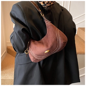 Detail of vintage brown suede shoulder bag with white contrast stitching and gold logo