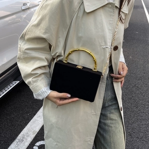 Détail du sac carré en velours noir avec poignée en bambou dorée et bandoulière