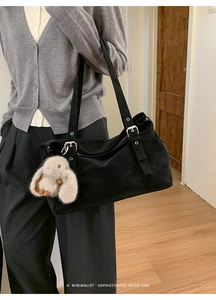 Détail du sac cabas noir avec boucles métalliques et un charmant lapin en peluche blanc