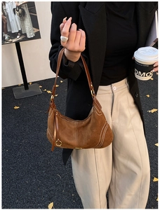 Brown suede hobo bag with contrast stitching and gold metal buckle in a street style shot