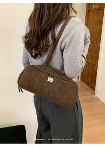 Detalle de bolso retro marrón oscuro con cierre de giro plateado y cremallera doble