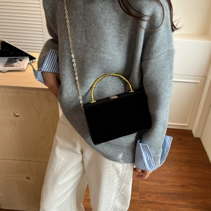 Détail d'un sac boîte en velours noir avec poignée en bambou doré et bandoulière