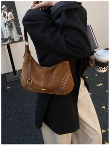 Close-up of a brown suede hobo bag with white stitching and gold hardware detail