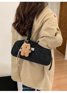 Detalle de bolso bandolera vintage de ante negro con cierre plateado y amuleto de oso