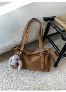 Detail of tan faux leather tote bag with soft texture and grey rabbit plush pendant