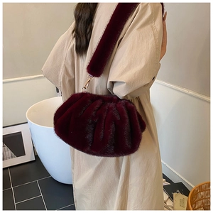 Close-up of fluffy dark burgundy faux fur bag texture with shiny gold metal hook details