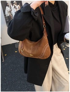 Brown suede hobo bag with contrast stitching and gold hardware on model shoulder