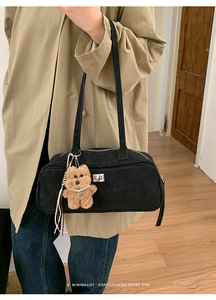 Detalle del bolso Boston de ante negro con colgante de osito de peluche y cierre metálico