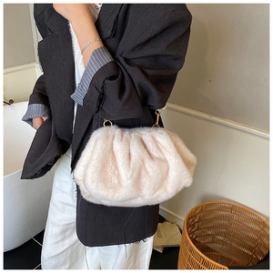 Detail of soft off-white faux fur plush handbag with elegant gold metal ring and pleats