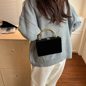 Détail du sac boîte en velours noir avec poignée en bambou doré et bandoulière