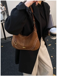 Close-up of brown suede hobo bag with white contrast stitching and gold metal hardware