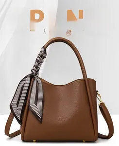 Close-up of brown litchi pattern leather bucket bag with decorative striped silk scarf