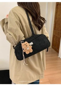 Detalle de bolso de hombro en ante negro con cierre plateado y colgante de osito