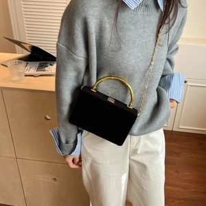 Détail du sac boîte en velours noir avec poignée en bambou dorée et bandoulière chaîne