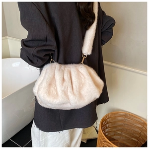 Detail of plush pleated shoulder bag with warm faux fur texture and gold hardware
