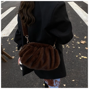 Detail of a dark brown faux fur pouch bag with textured plush finish and metal hook