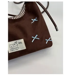 Detail of coffee suede tote bag with blue silk bows, white pearls and dog cartoon patch