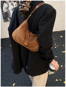 Brown suede hobo bag with contrast stitching shown on shoulder over black blazer