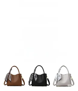 Detailed view of three textured leather bucket bags in brown, black, and grey with silk scarves