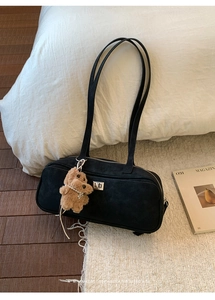 Detalle del bolso de hombro negro minimalista con un colgante de oso de peluche y perlas