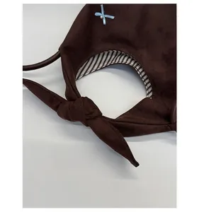 Detail of dark brown suede bag with elegant bow knot and striped lining texture