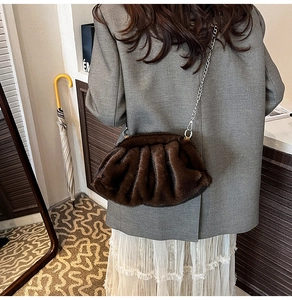 Détail du sac nuage en peluche marron foncé avec bandoulière chaîne sur un modèle