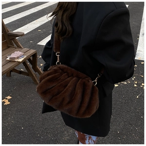 Close-up of the plush pleated texture and golden metal hooks on this dark brown cloud bag