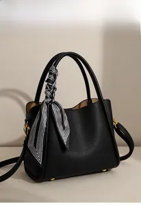 Detail of black pebbled leather bucket bag with a striped silk scarf wrapped handle