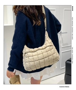 Close-up of beige quilted puffy shoulder bag showing soft pleated nylon texture and zipper