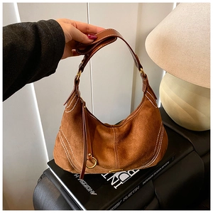 Detail of brown suede crescent bag with white contrast stitching and gold metal buckle