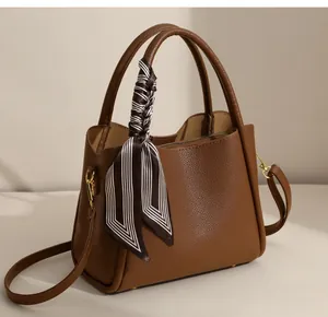 Close-up of brown pebbled leather tote bag with silk scarf and gold hardware accents