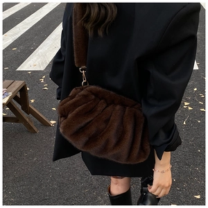 Close-up of brown faux fur crossbody bag with soft cloud pleats and gold buckle detail