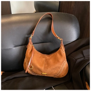 Detail of brown suede shoulder bag featuring white contrast stitching and long tassel zipper