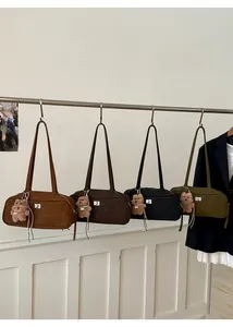 Detalle de cuatro bolsos de hombro en ante sintético de colores con colgante de oso