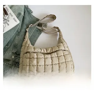 Detail of beige quilted cotton bag featuring puffer texture and matching wide shoulder strap