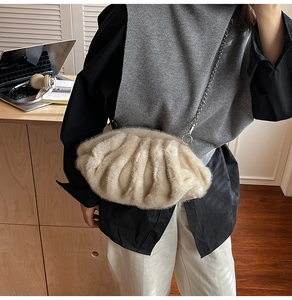 Détail du sac nuage en fausse fourrure beige avec chaîne argentée dans un bureau