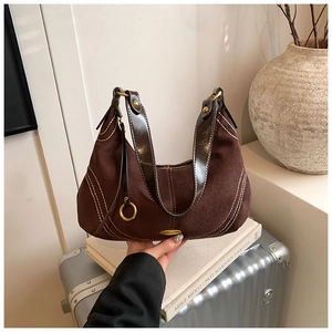 Close-up of retro brown suede bag with white stitching on a silver suitcase