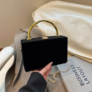Détail du sac à main rectangulaire en velours noir avec poignée en bambou doré