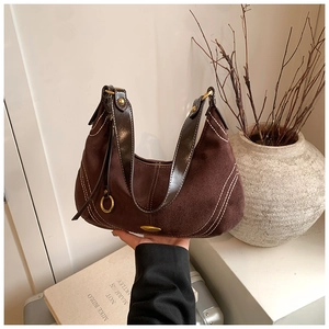 Close-up of brown suede shoulder bag with white stitching and gold metal buckle detail