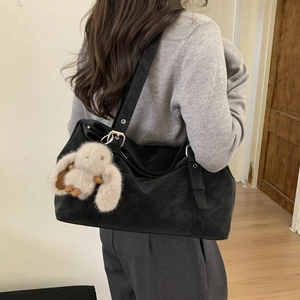 Large black matte shoulder tote bag with a cute plush rabbit pendant shown on a model