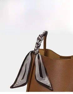 Close-up of brown litchi pattern bucket bag with decorative striped silk scarf