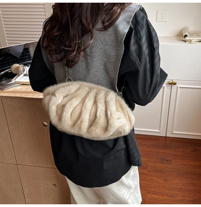 Détail d'un sac nuage en fausse fourrure beige avec une fine bandoulière en chaîne dorée