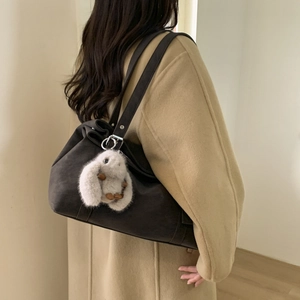 Retro minimalist large tote bag in dark coffee suede shown on shoulder with plush charm