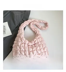 Detalle del bolso nube acolchado rosa con correa de hombro gruesa y textura plisada