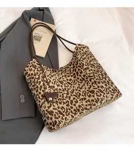 Gros plan sur le sac cabas imprimé léopard avec poignées brunes et charme en cuir