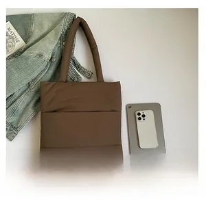 Flat lay of brown quilted puffer tote bag next to a tablet showing its large capacity